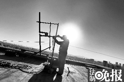 执法人员在楼顶拆除天线  摄/记者 柴程