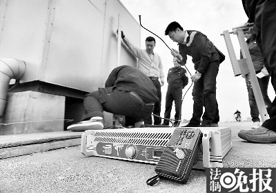 执法人员在楼顶拆除黑电台设备  摄/记者 柴程