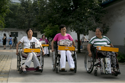 郑维芹与其他疗养者在参加完爱心仪式后推着轮椅回家，她落在了后面。中国青年网记者 孙钊 摄