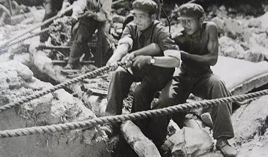 ▲在没有大型起重工具的情况下，解放军战士用双手拨开重物救人