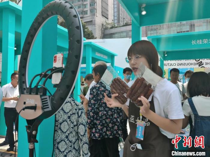 图为“巫姑腊味”展区工作人员正在直播。袁子寒 摄